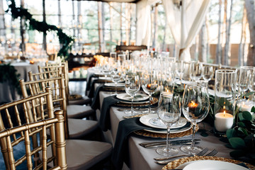 Decorated table with gold plates, candles and greens on the white tablecloth