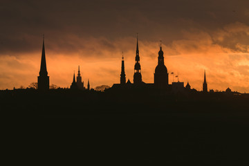 Naklejka premium City silhouette of Riga, Latvia in colorful morning sunset. Church towers and popular landmarks in background with stunning yellow sky. 