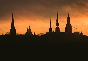 Naklejka premium City silhouette of Riga, Latvia in colorful morning sunset. Church towers and popular landmarks in background with stunning yellow sky. 
