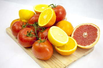 Tomato and orange on the white background with green leafs on th