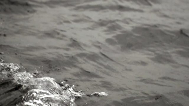 Waves from the ship in ocean slow motion. Black and white background.