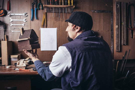 Amateur Carpenter With Wooden Birdhouse In Workshop