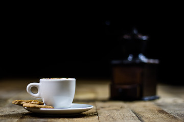Freshly brewed coffee in cups on a wooden table with a milling mill