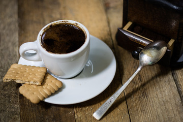 Freshly brewed coffee in cups on a wooden table with a milling mill