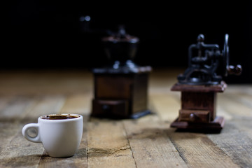 Freshly brewed coffee in cups on a wooden table with a milling mill