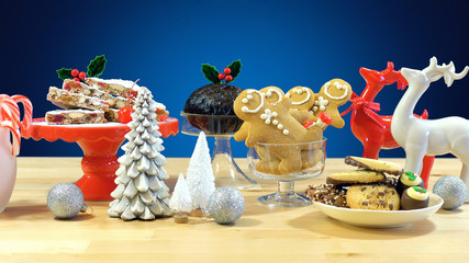 Festive table with traditional English and European style Christmas food including panforte cake, plum pudding, gingerbread cookies, and chocolate covered shortbread.  
