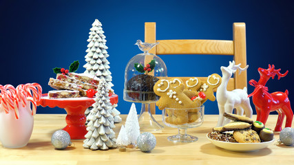 Festive table with traditional English and European style Christmas food including panforte cake, plum pudding, gingerbread cookies, and chocolate covered shortbread.  