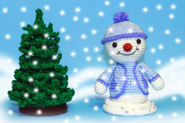 a snowman stands near a Christmas tree on a blue background, it's snowing