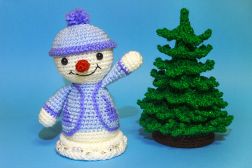 snowman waving his hand near the Christmas tree on a blue background
