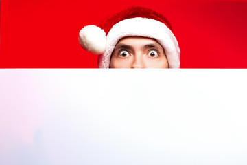 Christmas New Year concept, Stylish guy santa hat very surprised with white paper bottom and red glow background with place for text