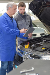 student mechanic learning from teacher in automotive vocational school