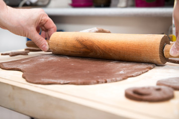 Baking gingerbreads. The family is preparing a gingerbread. The woman is rolling the dough. Preparing for Christmas, time for the family, cooking together and baking the concept. 