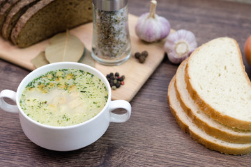 Mushroom soup with croutons in a white dish is on a wooden table.