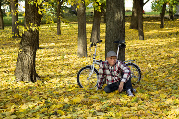 Fototapeta na wymiar Senior and his bicycle in autumn park.