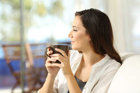 Pensive woman holding a coffee mug looking away