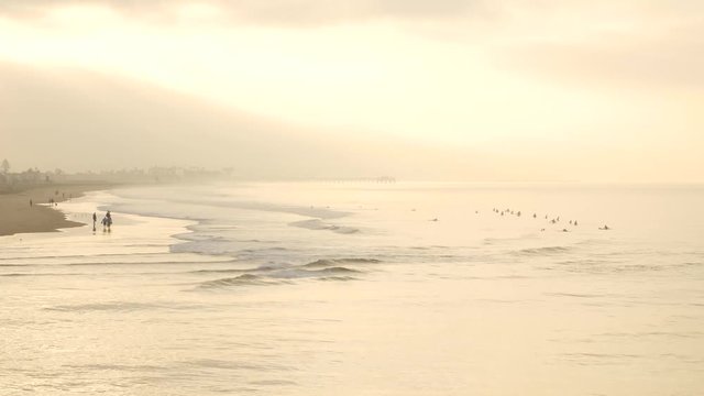 Surfers enjoy the waves at sunrise in Newport Beach, CA.