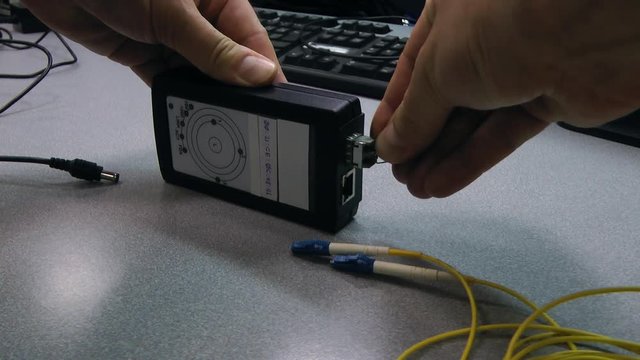 IT engineer insert optical patch cord in tested device.