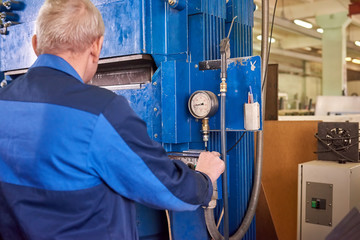Man operating hydraulic press machine. Factory worker and equipment.