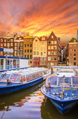 Traditional old buildings and boats at sunset in Amsterdam, Netherlands. - obrazy, fototapety, plakaty