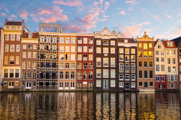 Naklejka premium Traditional old buildings and boats at sunset in Amsterdam, Netherlands.