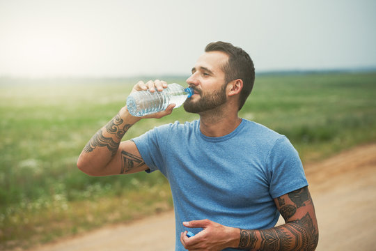 bearded man drinking bottle of water