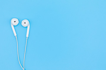 Top view of White Earphones on Blue background. Copy space. Music is my life concept