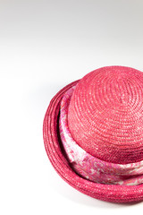 Top view of woman's pink straw hat with scarf band, on white, copy space, vertical aspect