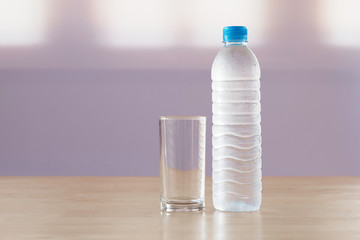 drinking water in plastic bottle with glass on table