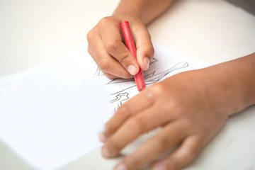 Child hand coloring on cartoon paper with color crayons