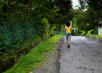 Fototapeta premium Lady Traveler walking down a road with Greenery