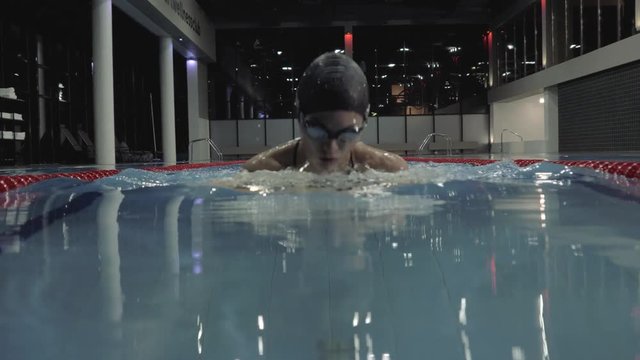 Sports woman floating breaststroke style in blue water swimming pool