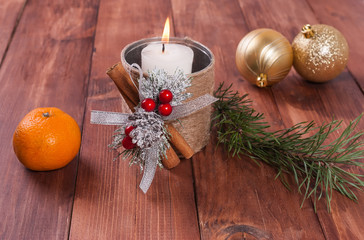 Hot white candle  and a Christmas ball on a wooden background