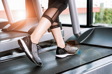 female muscular feet in sneakers running on treadmill at gym