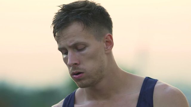 Handsome street fighter wearily wiping sweat and trying to recover after losing