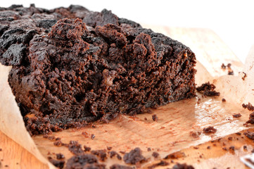 juicy Brownie cake  cut close-up  with baking paper on white background 
