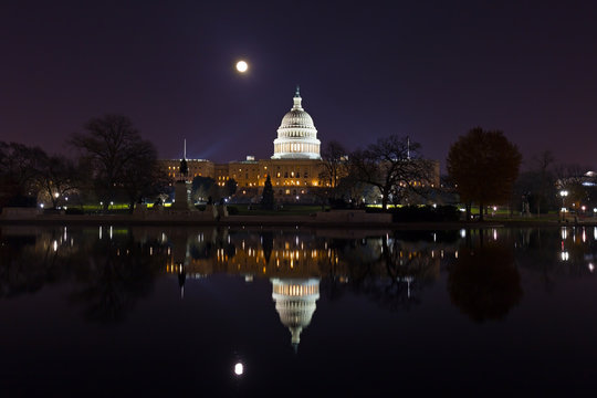 Capitol Hill panorama at night during super moon. Calm water of the pool with reflection of the dome.