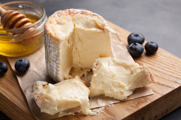 Closeup of Mature cheese on a wooden Board. Soft cheese with honey and blueberries