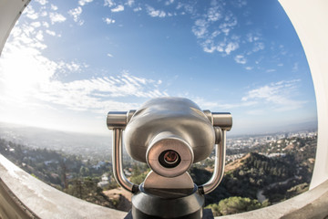 A shiny telescope viewfinder overlooking a beautiful scenery from a historical building window