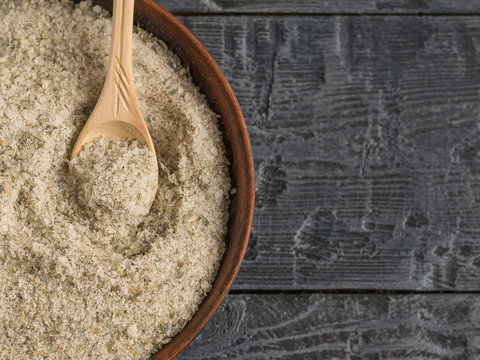 Bowl filled with salt with herbs and a tablespoon of light wood on the table. The view from the top.