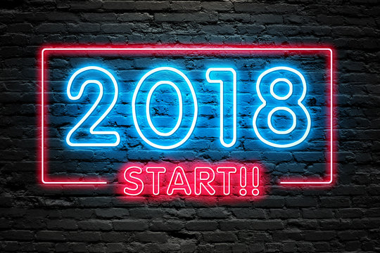 READY FOR 2018 NEW YEAR concept. 2018 START text fluorescent Neon tube Sign on dark brick wall. Front view. Can be used for online banner ads or background. night moment.