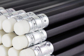 Close up of stacked new black pencils with whited erasers.