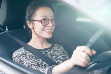 Attractive cute young asian woman in casual wear looking forward while driving a car. smile and happy time to travel or rest concept. filtered image. soft light effect added. fasten seat belt.