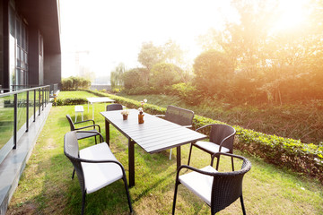 Fototapeta premium table and chairs near modern building with sunbeam