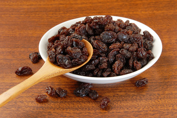Black raisins on a wood spoon