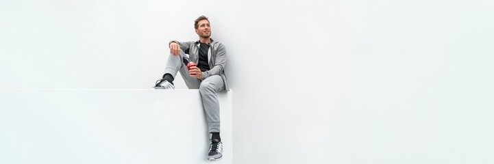 Ftiness sport man drinking smoothie workout banner relaxing at home in gym jogging pants activewear...
