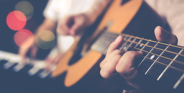 Guy Jamming Acoustic Guitar With Piano Player Background