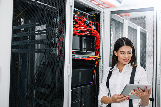Technician using tablet pc while analysing server in large data center