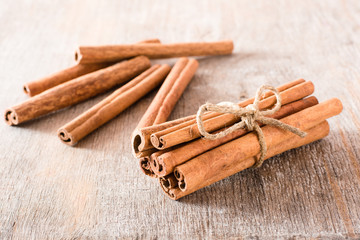 Cinnamon sticks, tied with a rope, lie on a wooden table. Fresh spice