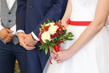 Wedding bouquet in hands of bride. The bride and groom in the registry office