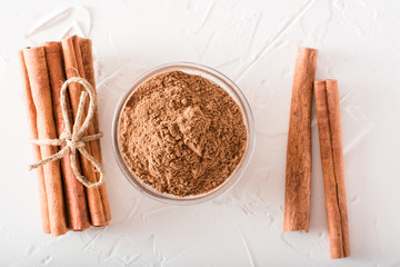 Cinnamon sticks, tied with a rope, and ground cinnamon in a bowl lie on the table. Top view